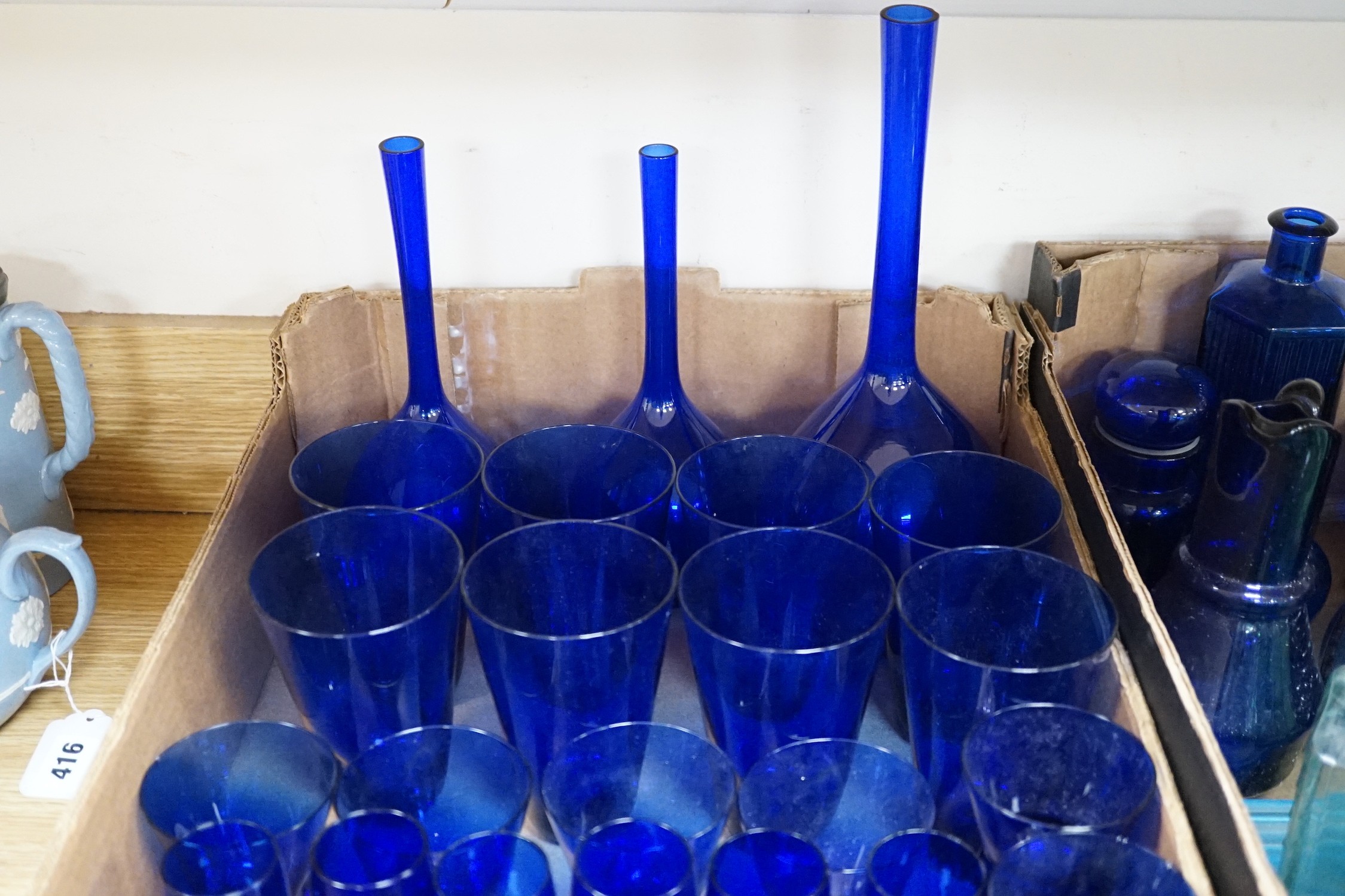 A collection of dark blue, green and turquoise coloured glassware, including three long stemmed glasses